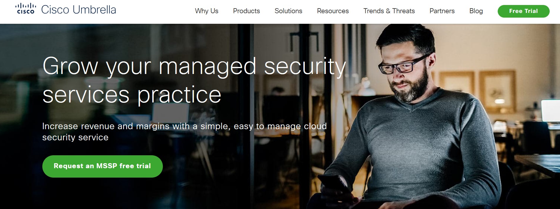 Cisco Umbrella Image: A bearded man with glasses is seated, using his smartphone, with the text overlay "Grow your managed security services practice. Increase revenue and margins with a simple, easy to manage cloud security service." The Cisco Umbrella logo is at the top left, and a "Request an MSSP free trial" button is at the bottom.