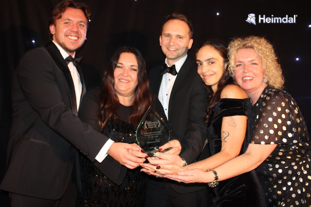 Five members of the Heimdal team in evening wear holding the Computing Security Awards trophy together